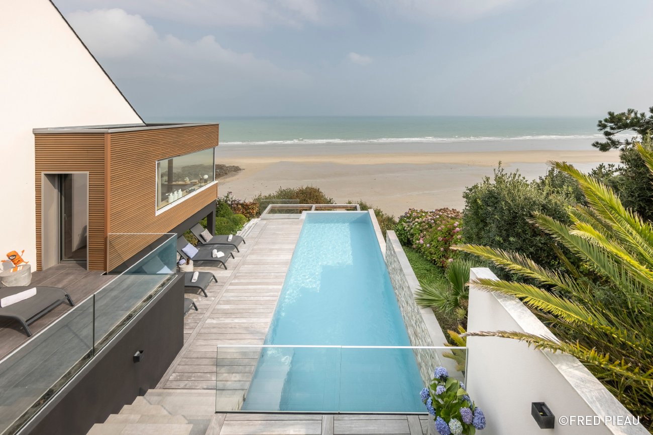 Catgorie : Piscine familiale de forme angulaire de moins de 40 m (rcompensant la ralisation d’une piscine de forme angulaire destine  un usage familial, dont la surface d’eau est infrieure  40 m) TROPHE D’OR EX QUO : ARMOREAL / EVERBLUE PISCINES Descriptif :Cette piscine angulaire, d’une surface de 9,5 x 3,2 m et d’une profondeur de 1,5 m, s’adapte  un terrain trs pentu avec accs difficile, grce  sa structure en bton bloc  bancher. Elle prsente un bassin  dbordement pour un rendu visuel lgant et un escalier droit en angle facilitant l’accs. Le choix des matriaux privilgie l’esthtique et la durabilit : PVC arm Armakor gris moyen pour le revtement, et bois Ip pour la plage et les margelles, offrant un rendu naturel et chaleureux parfaitement intgr au jardin. Une ralisation exemplaire qui combine technicit, design et adaptation au terrain, offrant confort et convivialit pour toute la famille. Crdit photo : Armoreal / Everblue Piscines