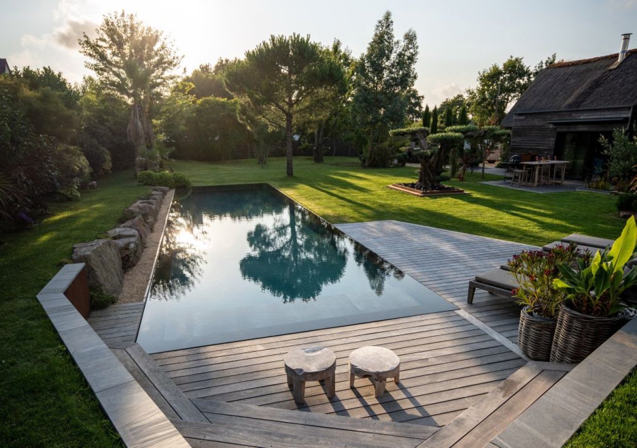 Catgorie : Couloir de nage TROPHE D’OR EX QUO : PISCINES DE FRANCE GURANDE Descriptif :Le modle Piscine miroir couloir de nage offre 16 x 3,75 m de longueur pour une exprience de nage optimale. Construit en maonnerie traditionnelle en bloc  bancher, il se distingue par son dbordement dans le gazon et son intgration harmonieuse au pied de blocs rocheux. Le bassin est habill d’une membrane arme grise anthracite, avec plage en bois Cumaru rouge et margelle en pierre de Balsate, crant un contraste lgant et naturel. Les quipements haut de gamme incluent pompe  chaleur Polaris 280, nage  contre-courant, rgulateur de pH, panneaux solaires, ainsi qu’un bassin  poissons et cuisine extrieure, alliant confort, cologie et convivialit. Une ralisation qui conjugue esthtique, performance et intgration paysagre, idale pour les amateurs de nage et de loisirs en extrieur. Crdit photo : Piscines de France Gurande